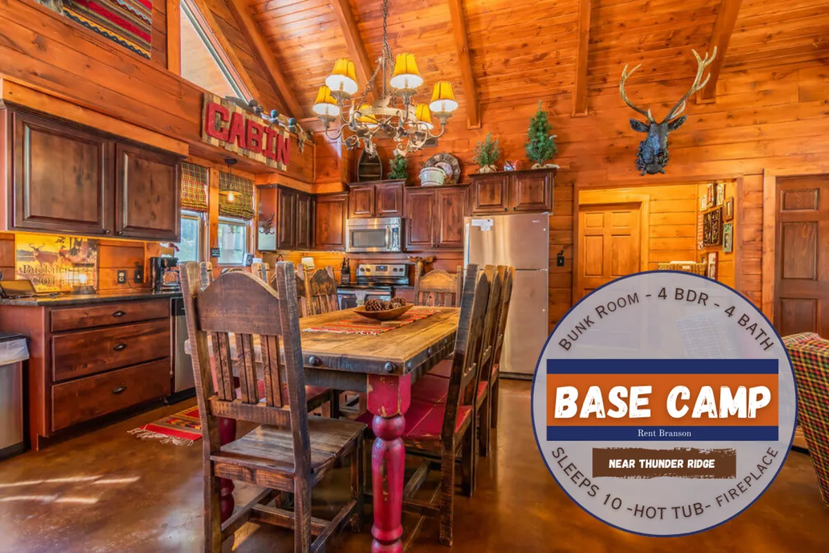 This image centers on a large wooden dining table with a distinctive chandelier above, rustic kitchen cabinets in the background, and antler decor on the wall. The scene exudes warmth and encourages gathering for meals or game nights.
