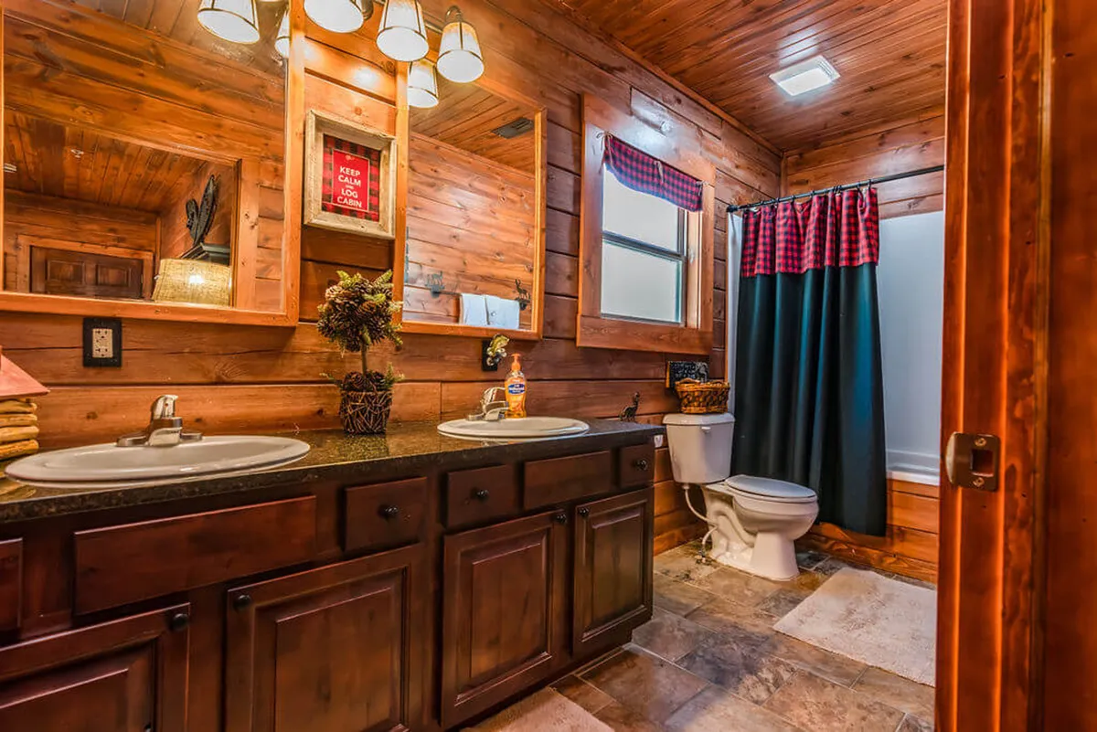 An inviting bathroom scene with double sink vanities, wooden cabinetry, framed mirrors, and tasteful decor. The space is bright and homey, perfect for morning routines or relaxing after a long day. The design emphasizes both function and a spa-like feel.